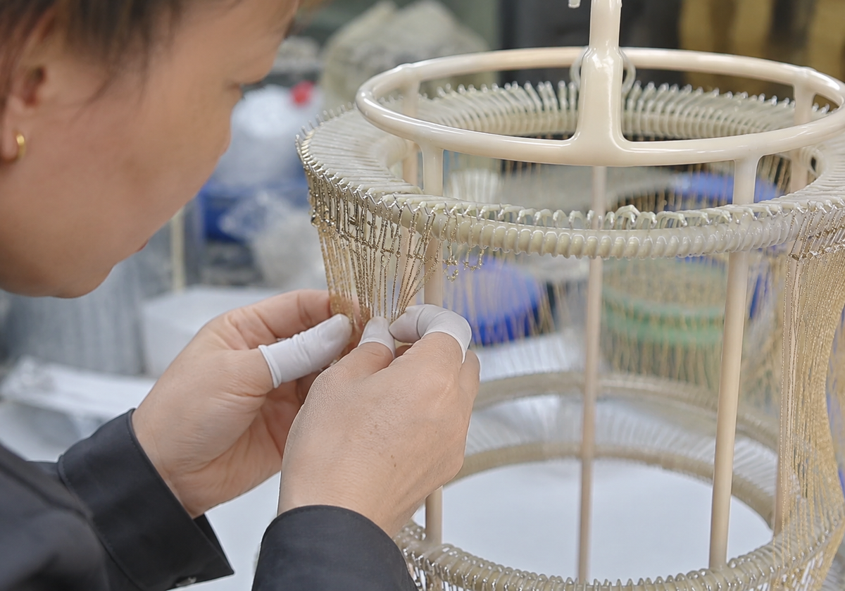 Chinese jewelry technician hanging jewelry components on an electroplating rack